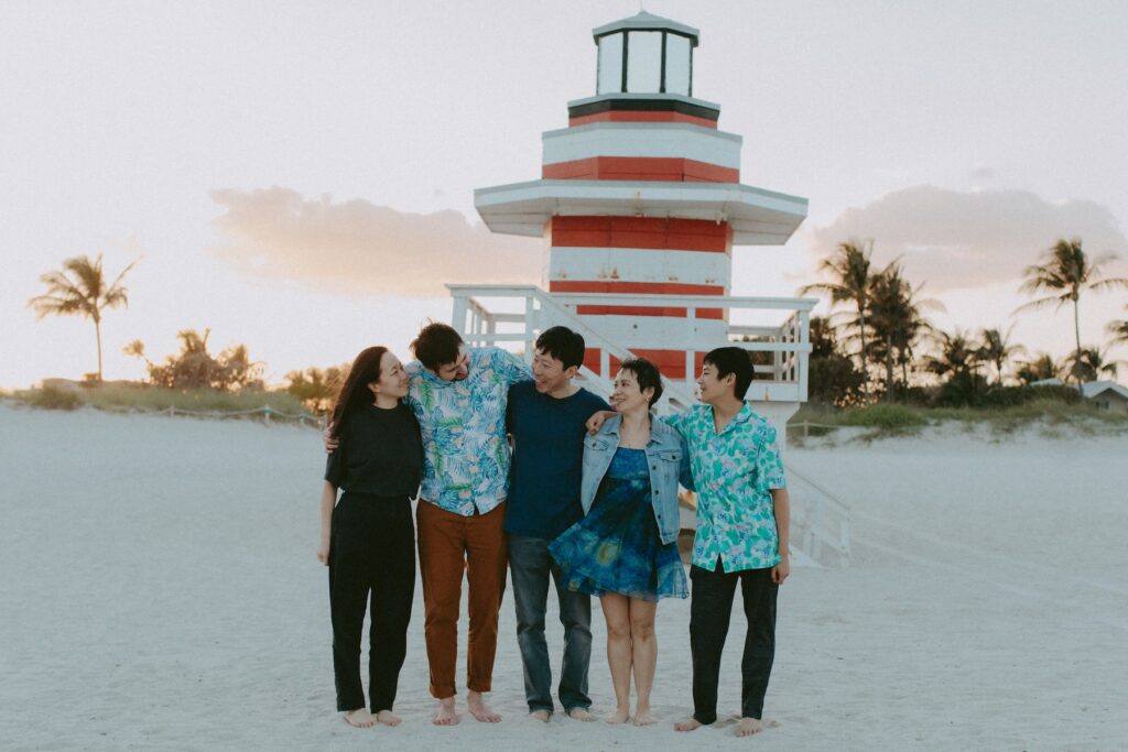 A family hugging on the beach in Miami, Florida at South Pointe Park & Beach on a family photoshoot with Flytographer.