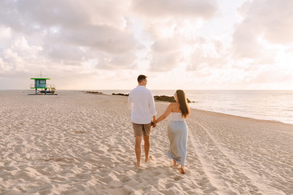 A couple walking on the beach in Miami, Florida at 26th street beach on a couples photoshoot with Flytographer.