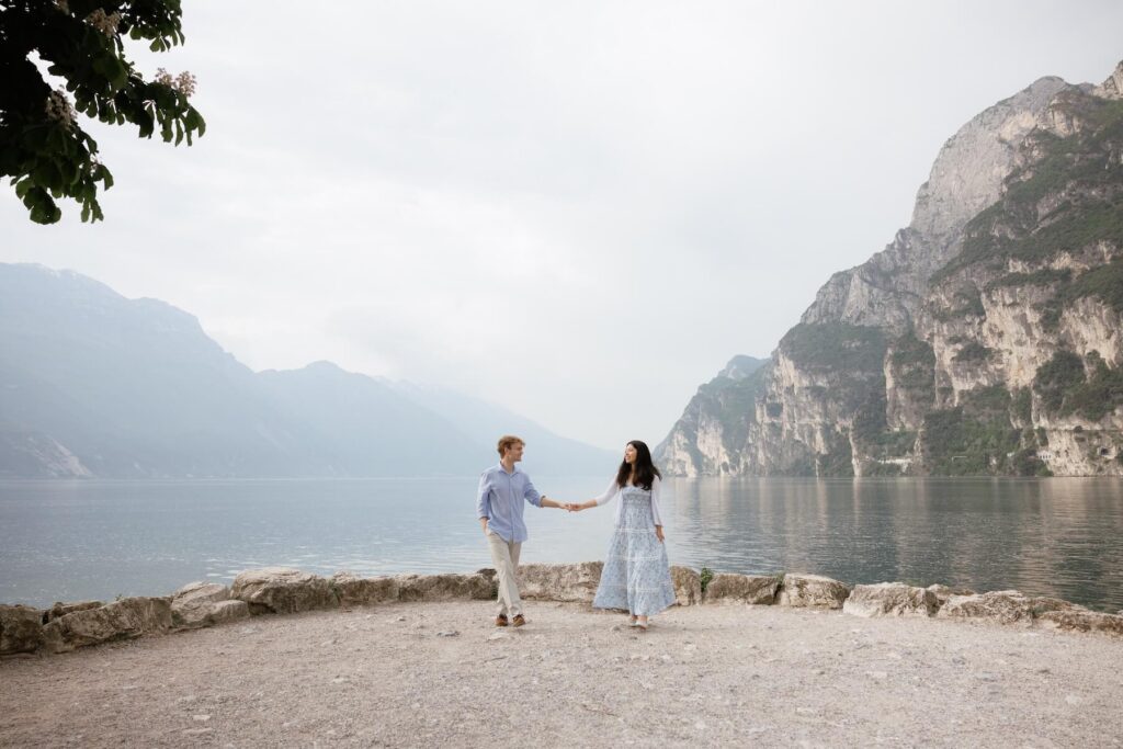 A couple walking in front of Lake Garda, which is one of the best places to visit in Italy, on a couples photoshoot with Flytographer.