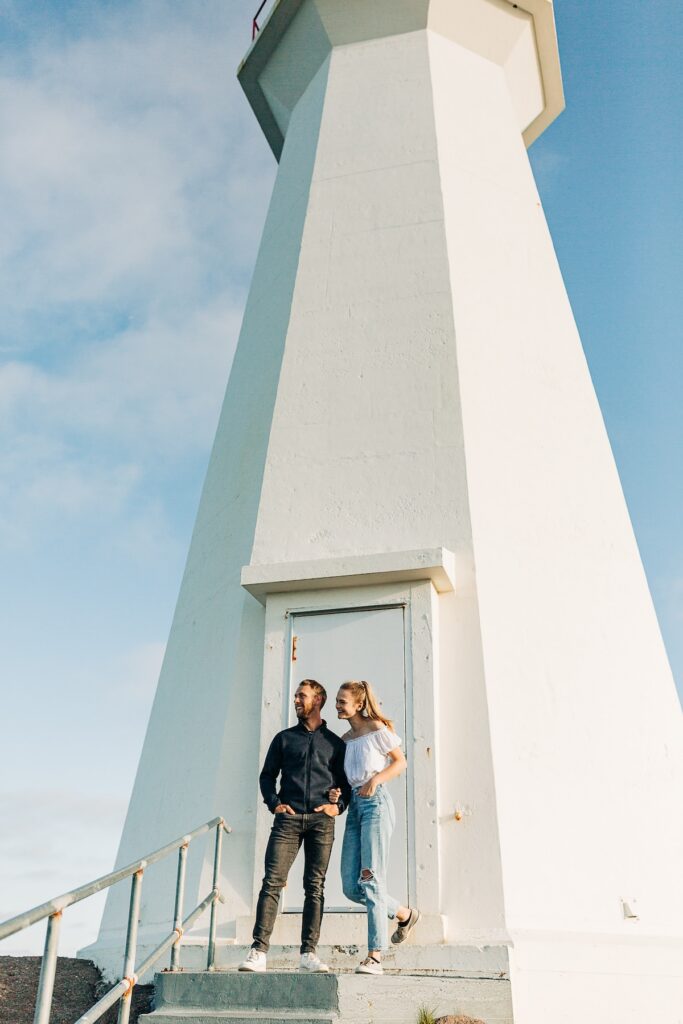 Couple looking at the view with a lighthouse behind them in St. John's Newfoundland on vacation in the summer captured by Flytographer