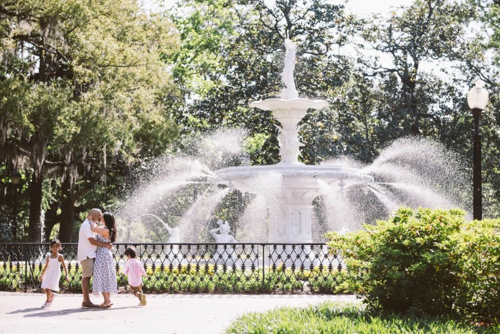 A family dancing by a fountain in Savannah, Georgia, one of the most European cities in North America on a photoshoot with Flytographer