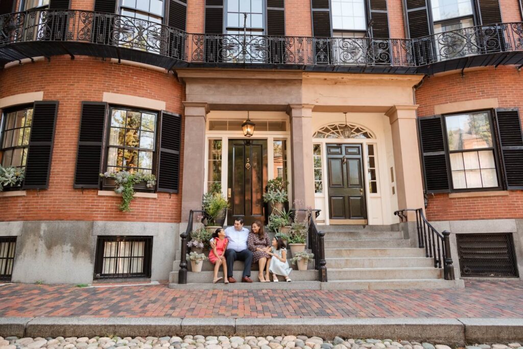 A family sitting on the sidewalk in Boston, MA, one of the most European cities in North America on a photoshoot with Flytographer