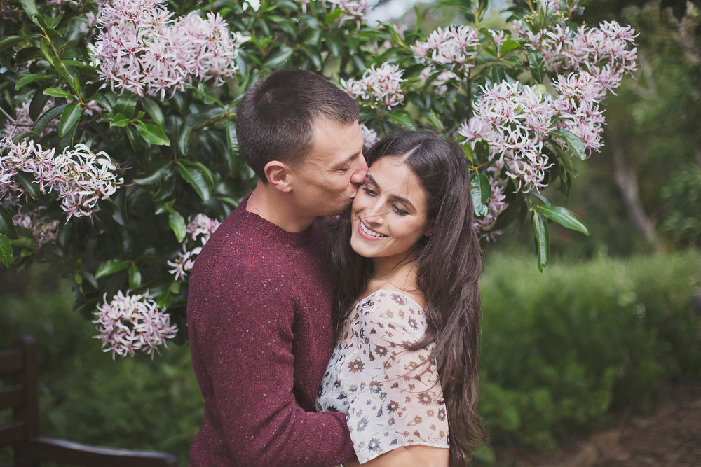 Man kissing his partner's cheek surrounded by flowers in Cape Town, South Africa