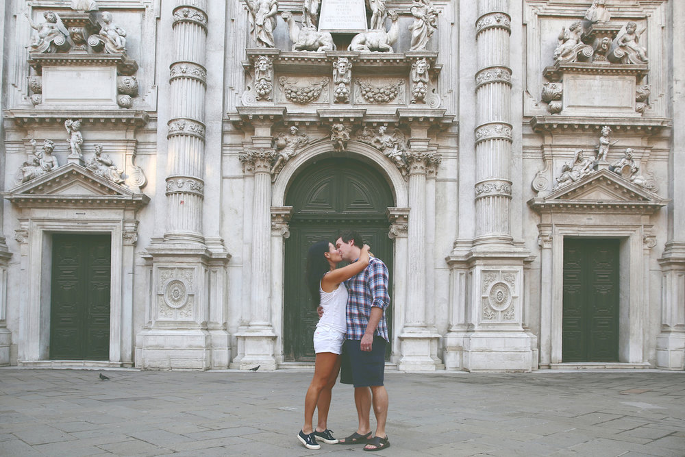 Couple kissing in front of green doorways on a couples trip in Venice, Italy