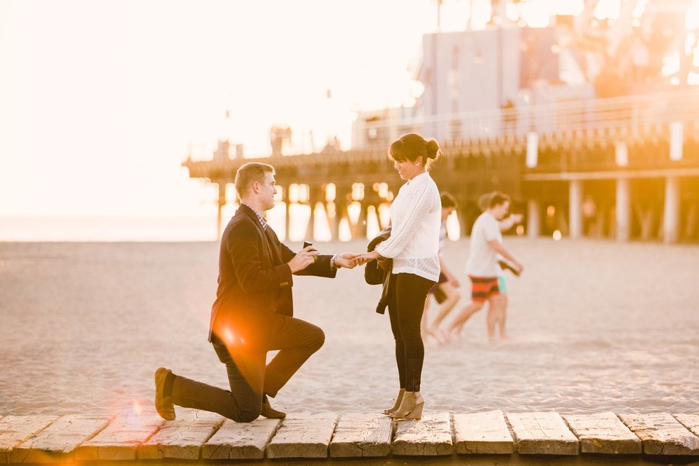 Man proposing to his partner on a boardwalk along a beach in Los Angeles, California USA